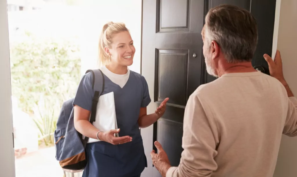 A female nurse from Community Care TASMANIA greeting an older man at the door