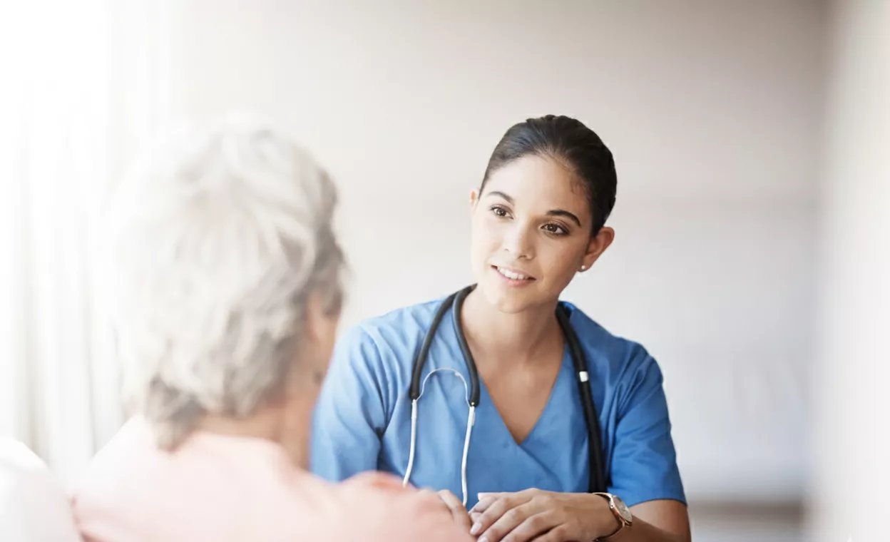 A nurse sitting with her older female patient