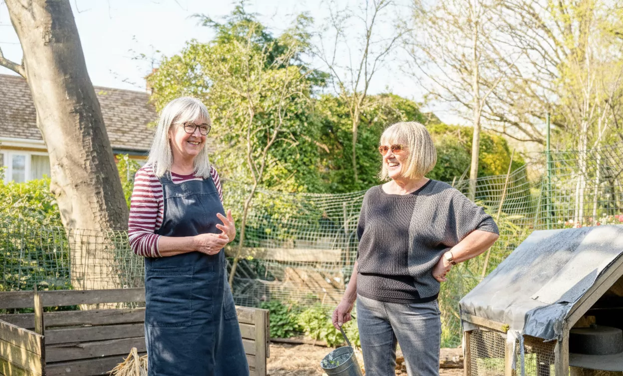 Two older women smiling at each other in the garden
